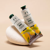Mango Hand Balm by The Body Shop 30 ML elegantly displayed against a soft beige backdrop and a decorative stone.