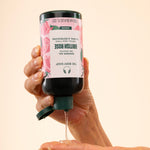 Hands dispensing The Body Shop British Rose Shower Gel 250ml, showing product texture against soft background.