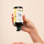 Person dispensing The Body Shop Mango Shower Gel 250 ML against soft beige background
