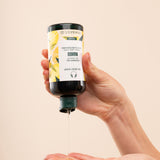 Person dispensing The Body Shop Mango Shower Gel 250 ML against soft beige background