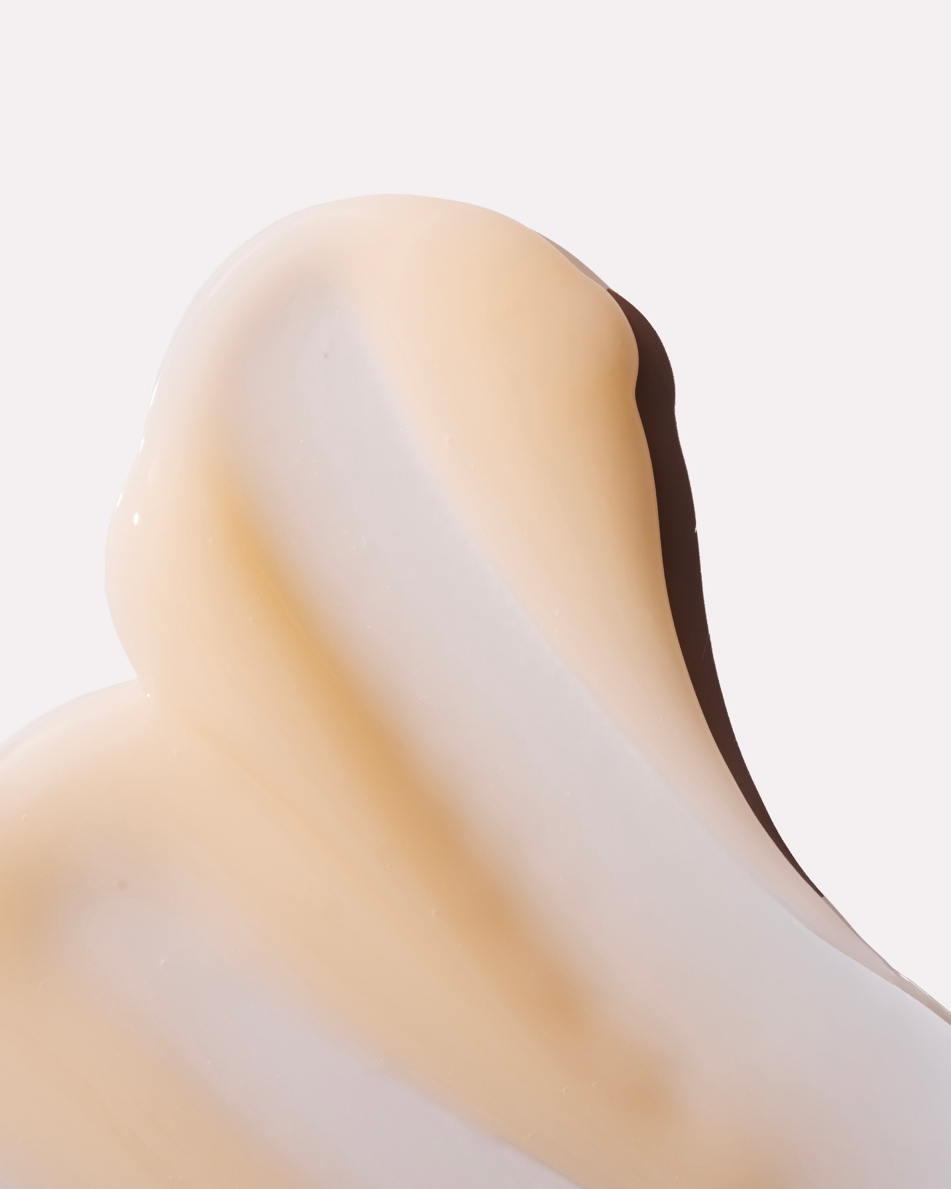 Close-up view of a creamy product displaying a smooth, blended texture on a neutral background.