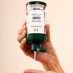 Hand dispensing The Body Shop Coconut Shower Cream 250 ML into palm, in relaxing bathroom setting