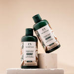 Two bottles of The Body Shop Coconut Shower Cream 250ml displayed on light backdrop, emphasizing design.
