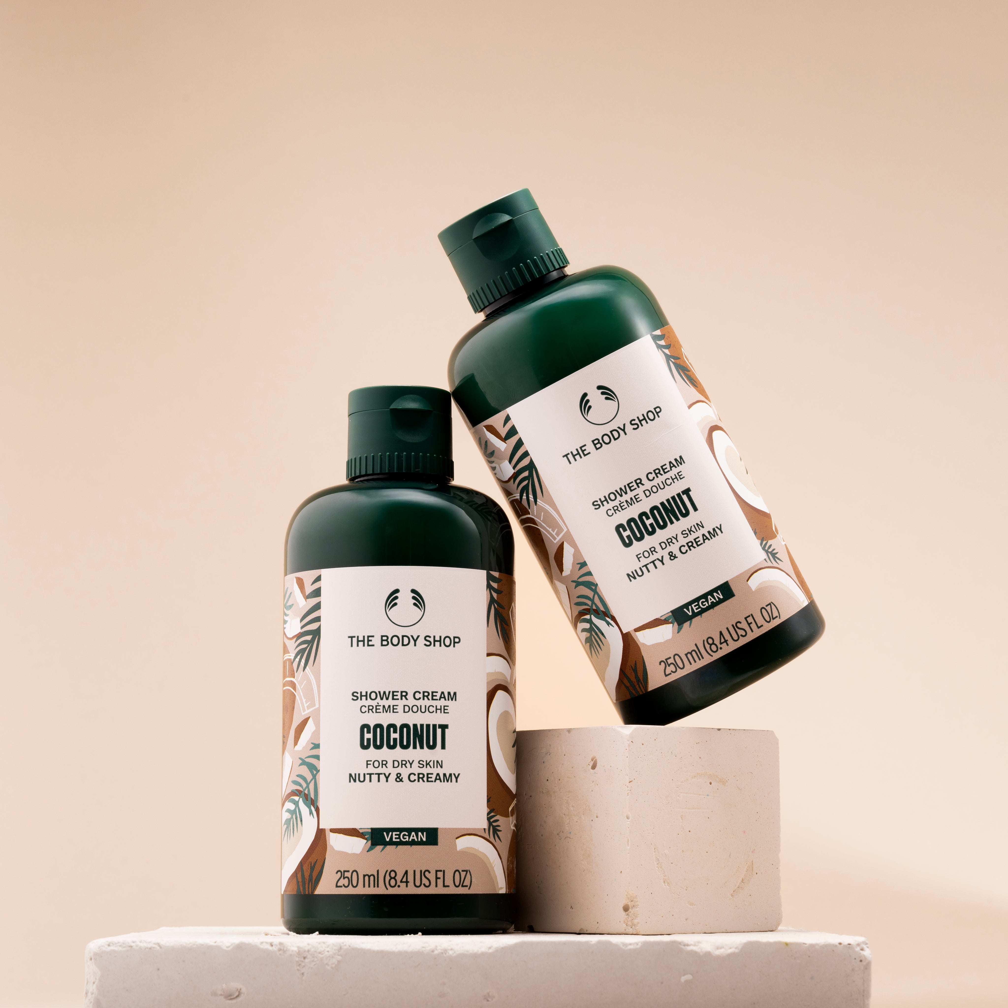 Two bottles of The Body Shop Coconut Shower Cream 250ml displayed on light backdrop, emphasizing design.