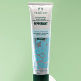 The Body Shop Peppermint Reviving Pumice Foot Scrub 100 ML displayed on smooth white stone against soft green background