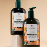 Two bottles of The Body Shop Pink Grapefruit Shower Gel 750 ML against a soft beige background.