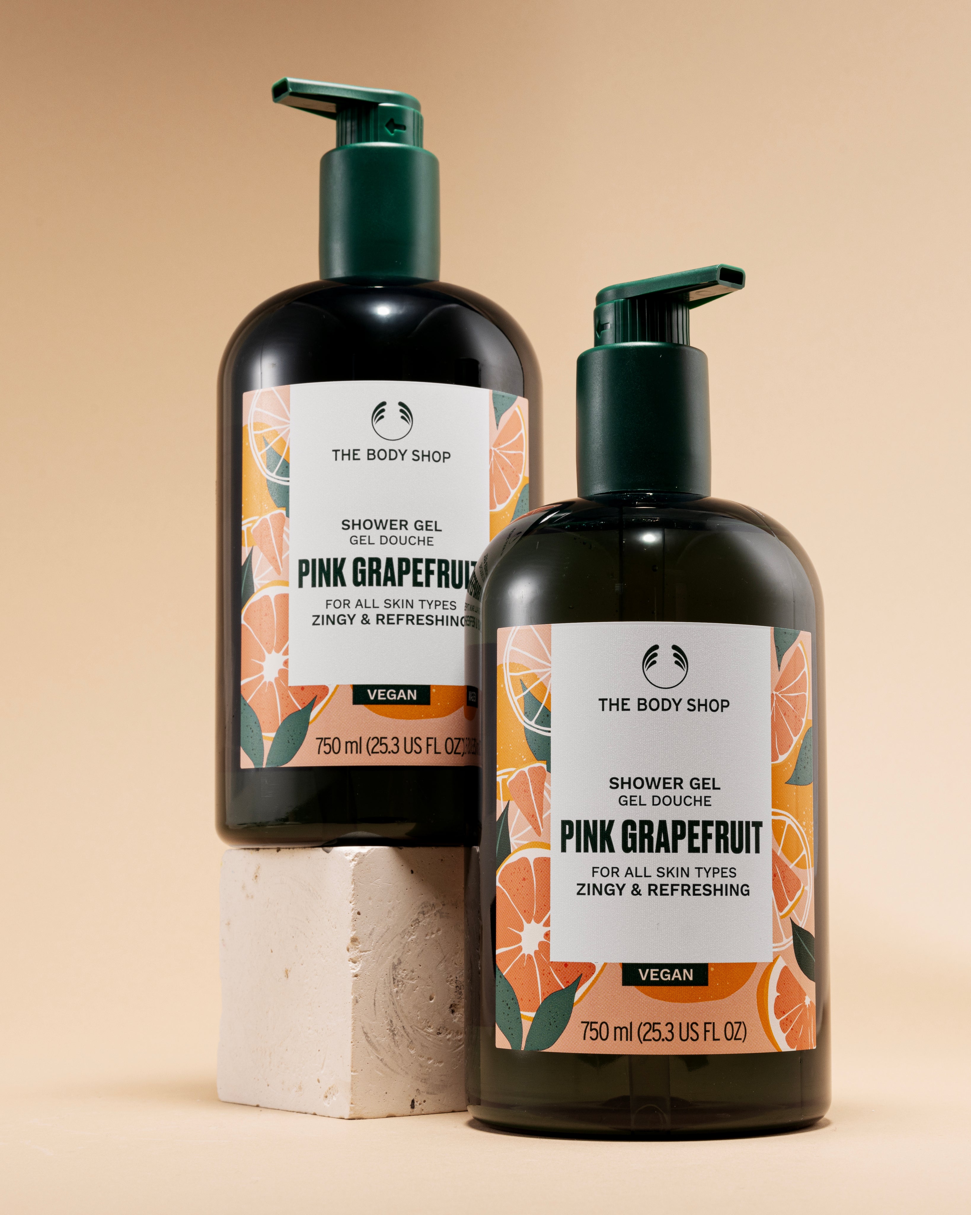 Two bottles of The Body Shop Pink Grapefruit Shower Gel 750 ML against a soft beige background.