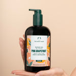 Hand holding The Body Shop Pink Grapefruit Shower Gel 750 ML against soft, neutral background