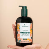 Hand holding The Body Shop Pink Grapefruit Shower Gel 750 ML against soft, neutral background