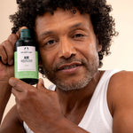 Man holding The Body Shop Aloe Soothing Toner 250 ML in light-colored studio setting