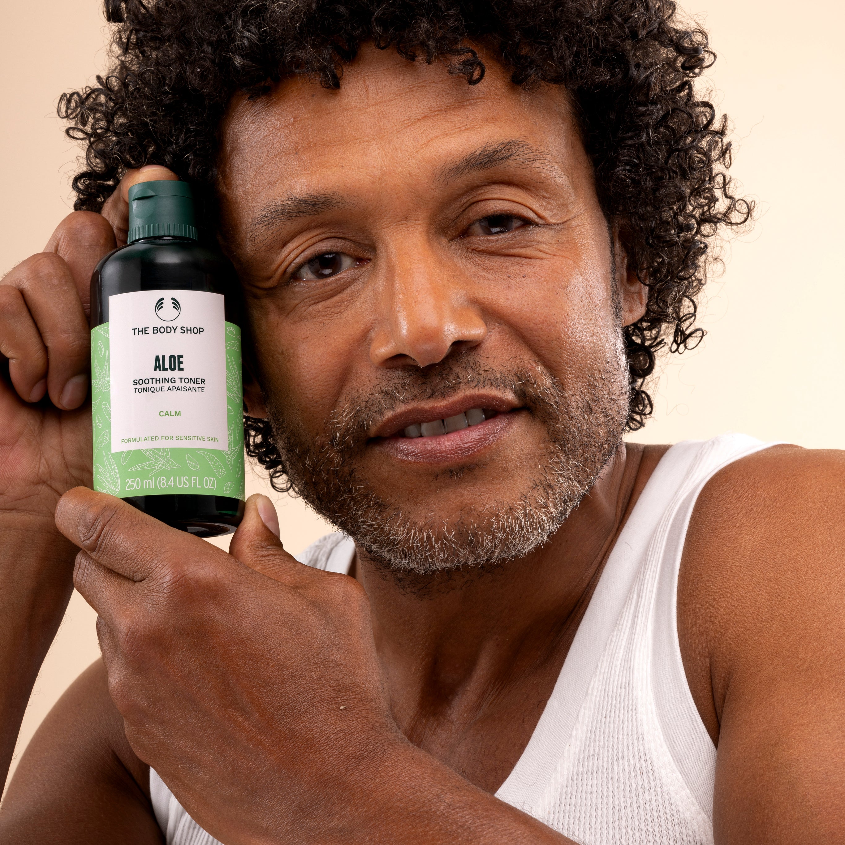 Man holding The Body Shop Aloe Soothing Toner 250 ML in light-colored studio setting