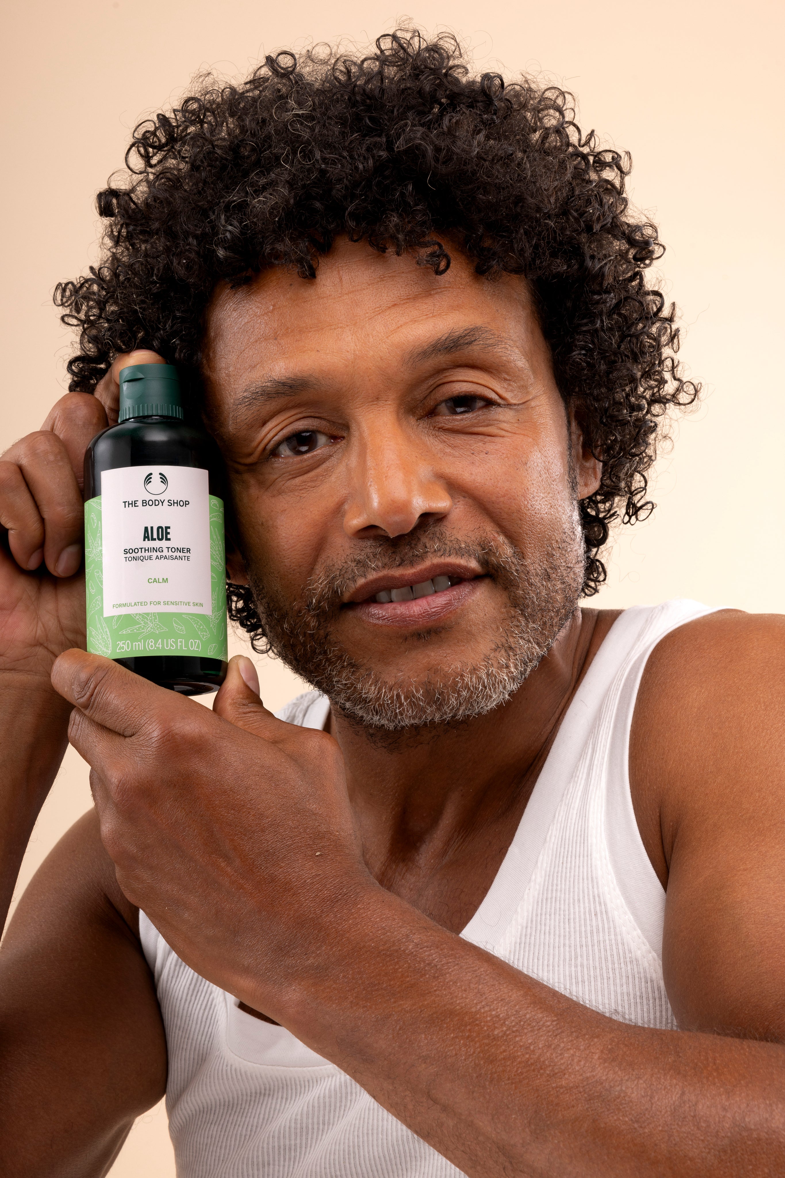Man holding The Body Shop Aloe Soothing Toner 250 ML in light-colored studio setting