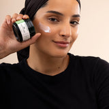 Woman applying The Body Shop Aloe Soothing Night Cream 50ml in a studio setting with a soft backdrop.