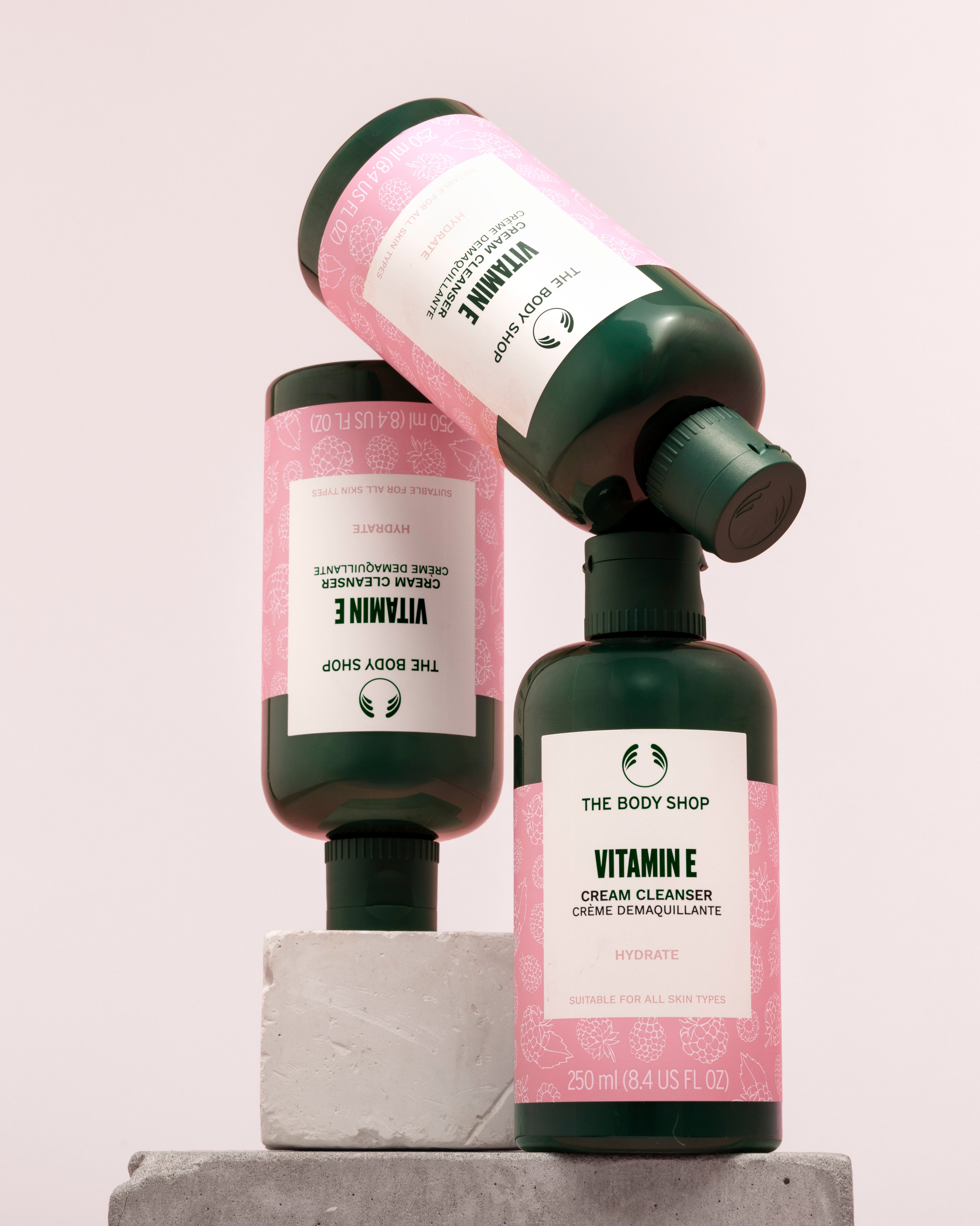 Visually appealing display of The Body Shop Vitamin E Cream Cleanser 250 ML on light backdrop with stone display.