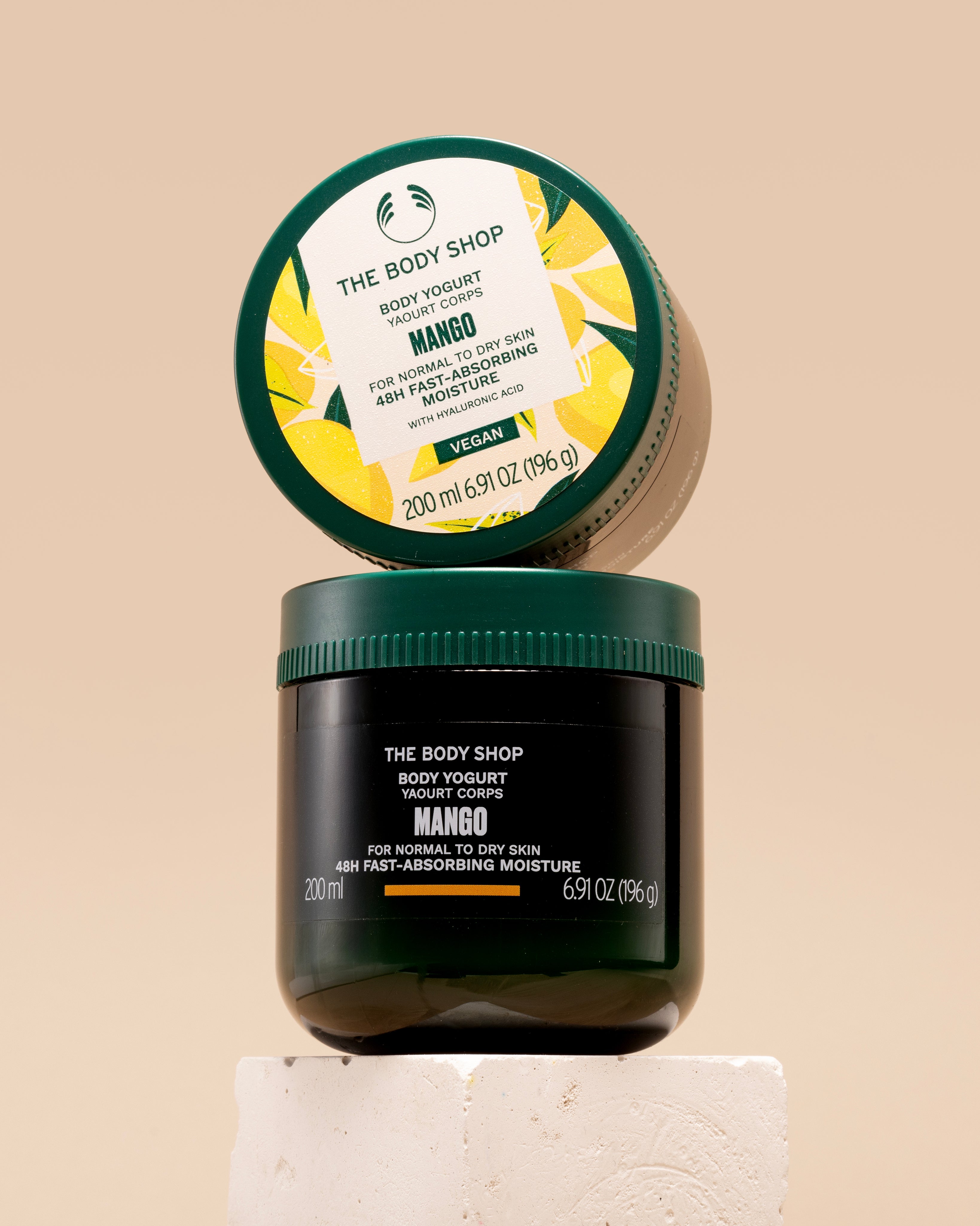 The Body Shop Mango Body Yogurt 200 ML elegantly displayed on a textured surface with a minimalist backdrop.