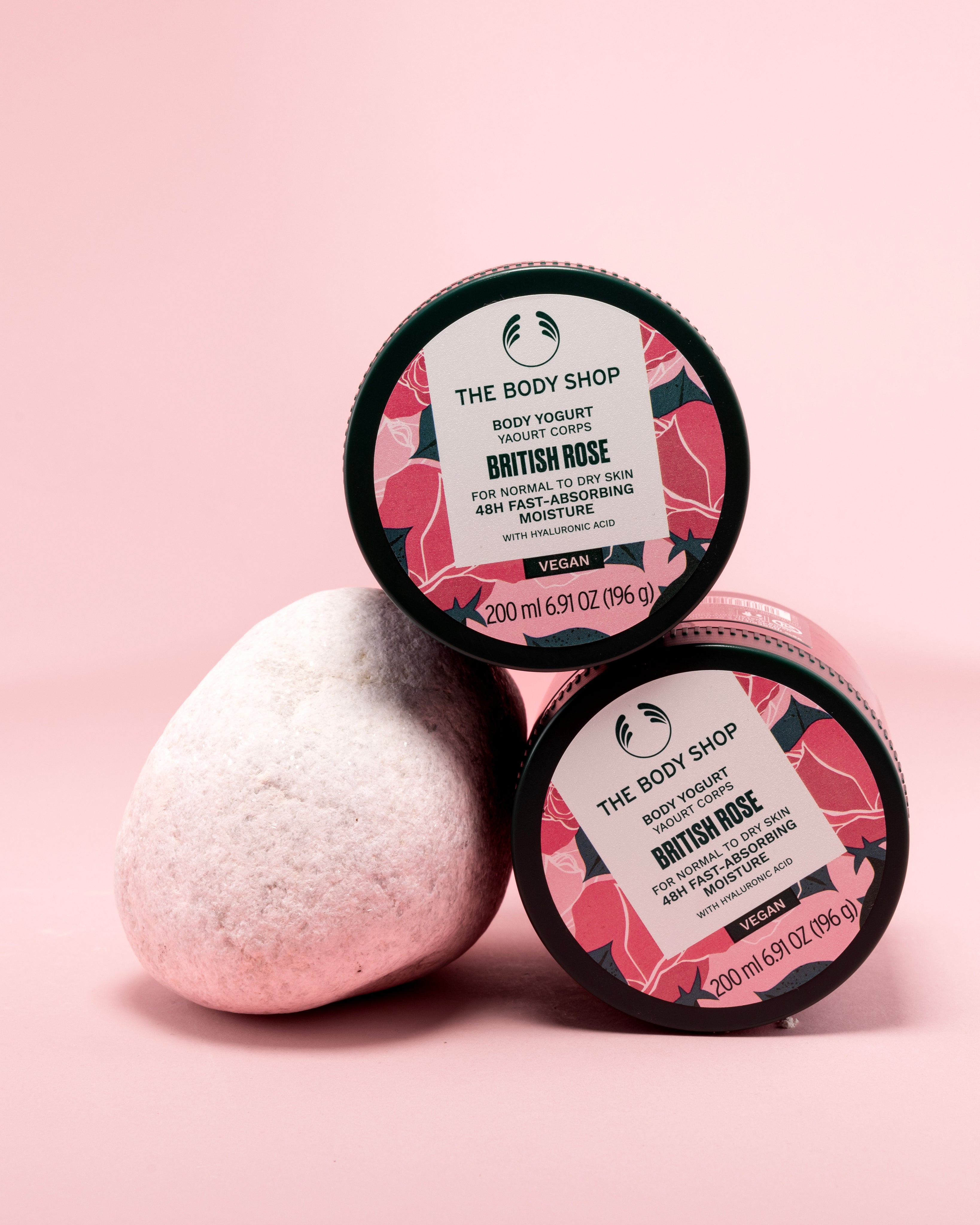 Two containers of The Body Shop British Rose Body Yogurt 200ml on a pink backdrop