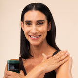 Woman applying The Body Shop Strawberry Body Yogurt 650g on her arm against a soft, neutral background.