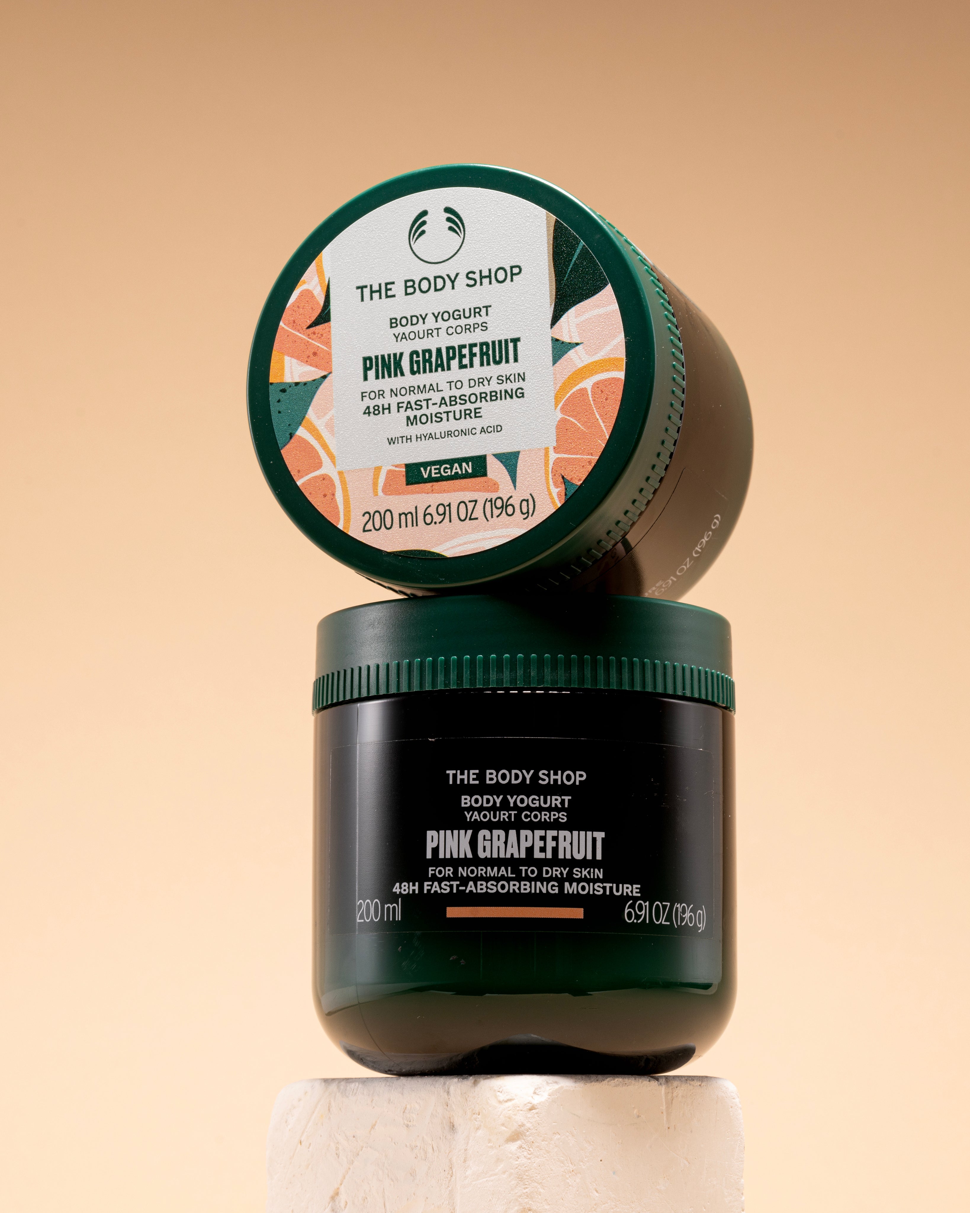 A stacked view of The Body Shop Pink Grapefruit Body Yogurt 200 ML on a light-colored pedestal.