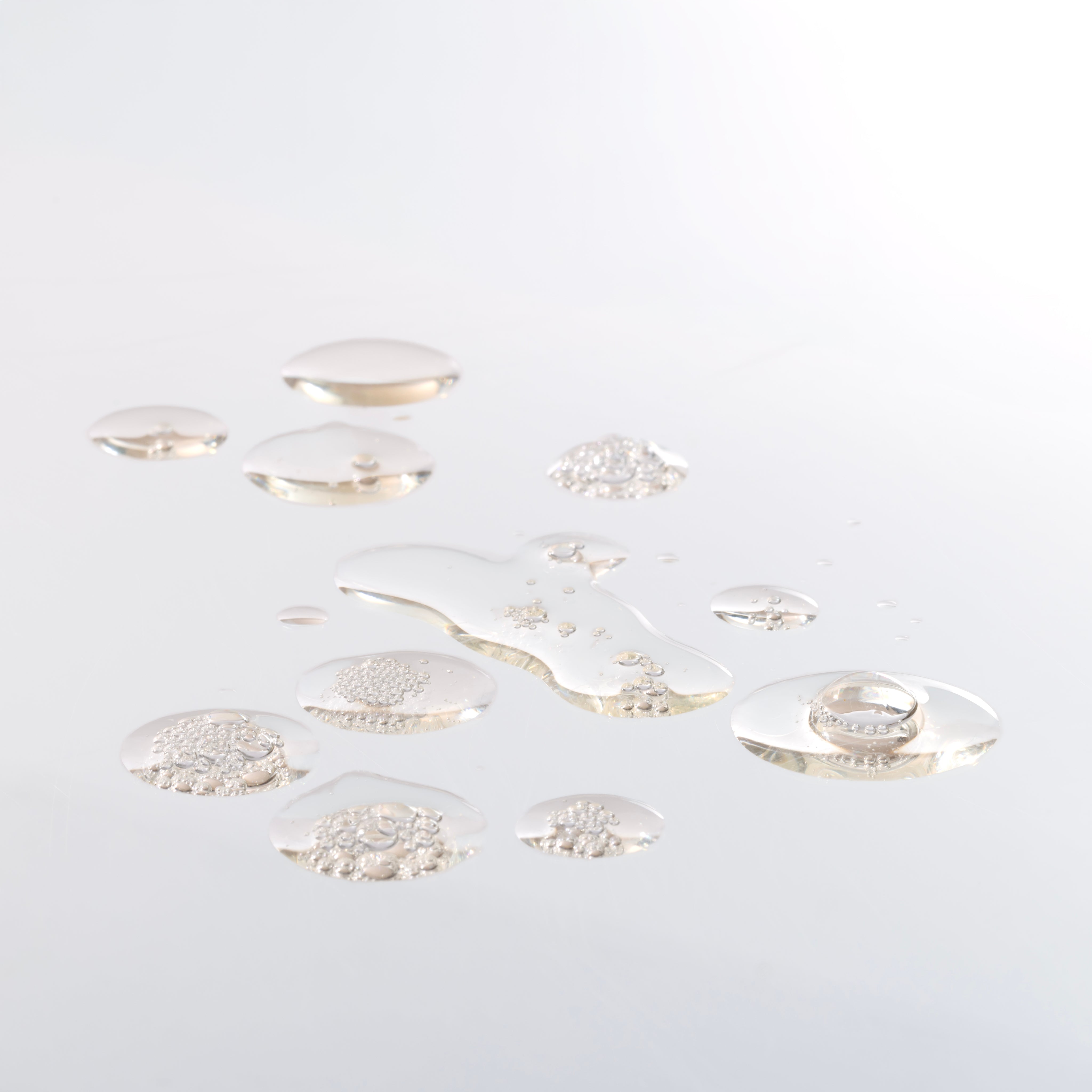 Artistic close-up showing droplets of ginger scalp serum on a clean surface, highlighting texture.