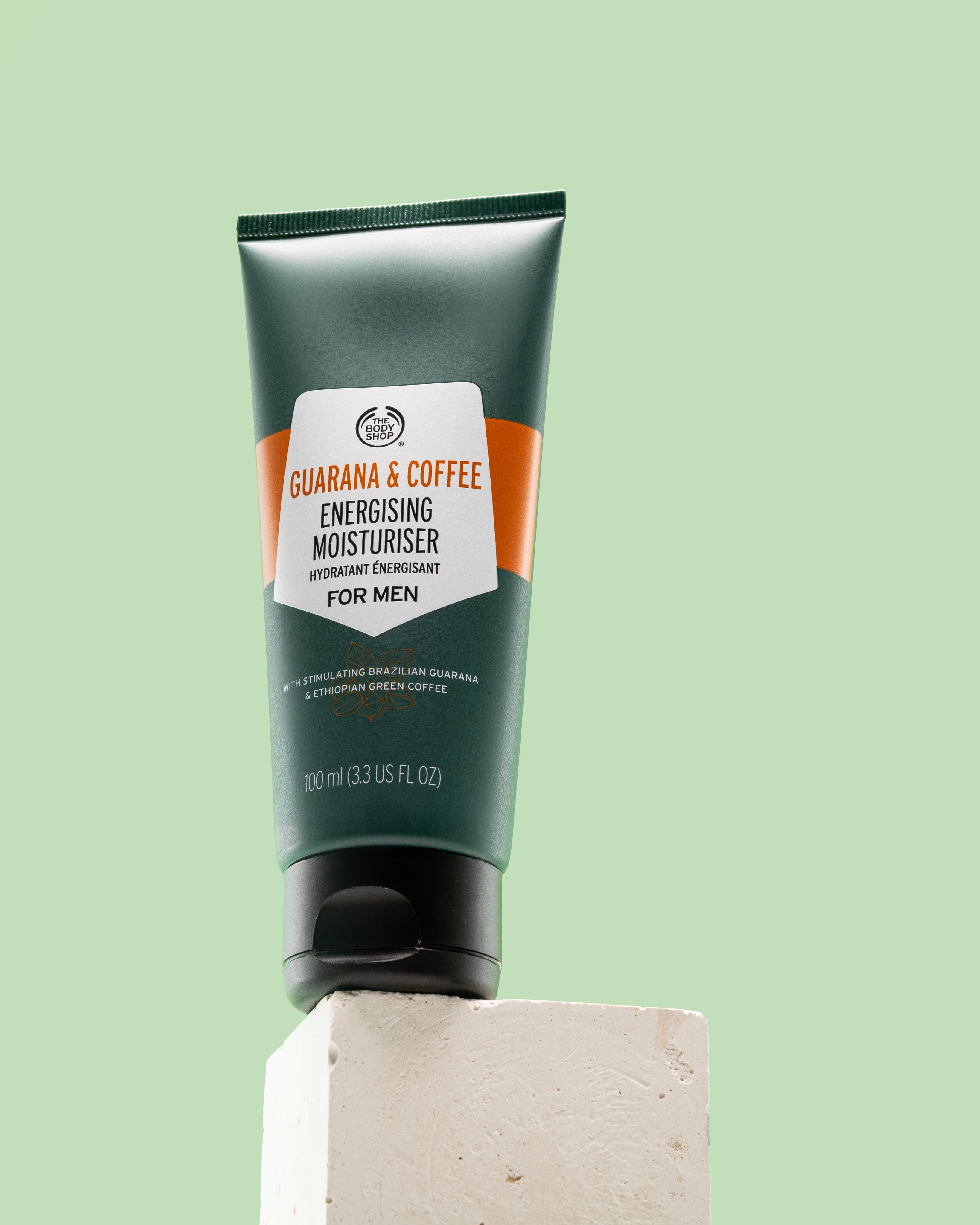 Guarana & Coffee Energising Moisturiser For Men 100 ML on white block against green background