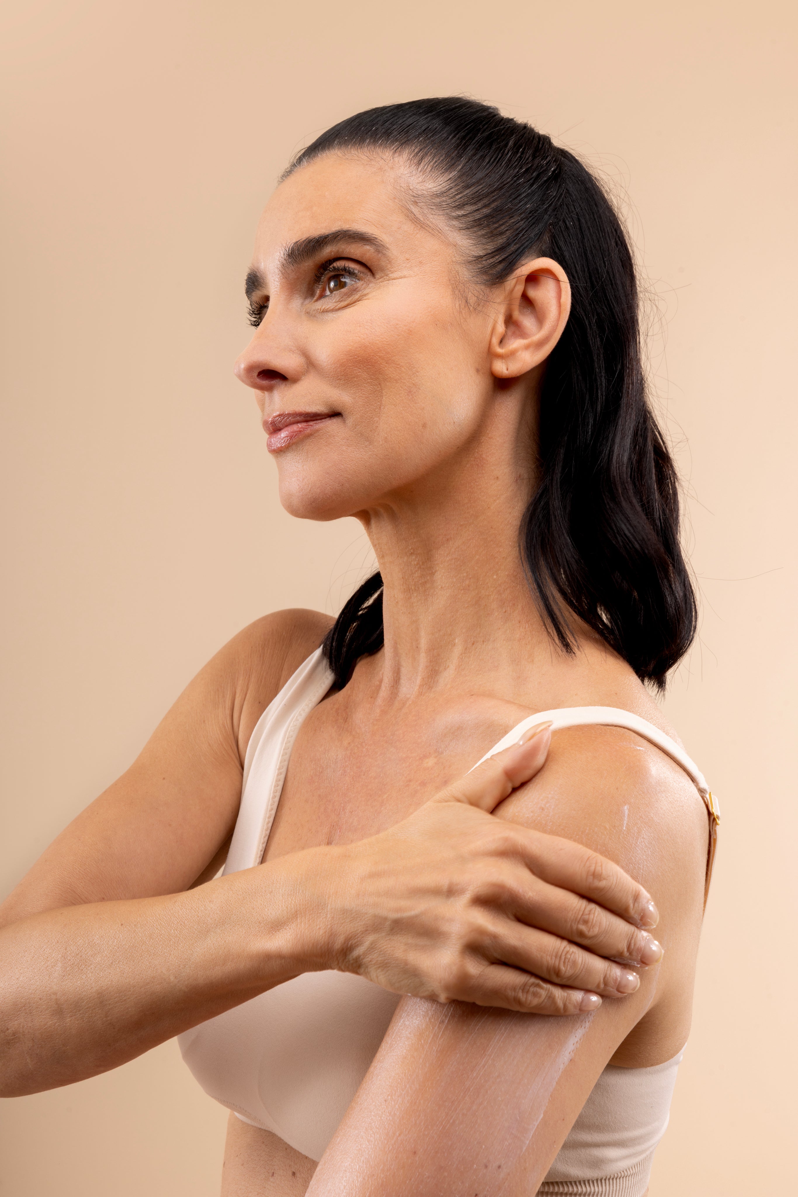 Woman applying Almond Milk Body Butter 200 ML against a soft, neutral backdrop, showcasing its moisturizing texture.