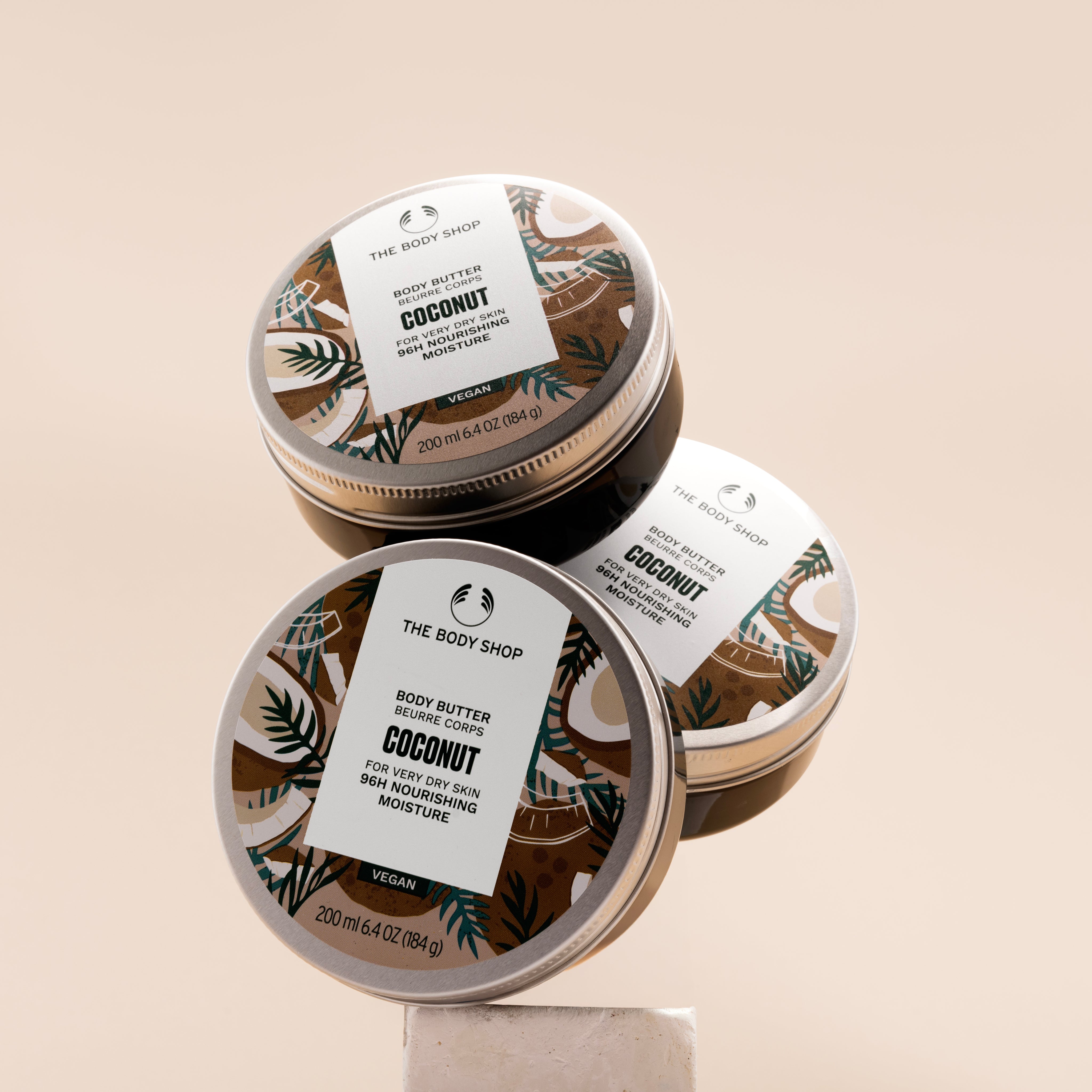 Three jars of The Body Shop Coconut Body Butter 200ml arranged on a clean surface, showcasing vibrant packaging.
