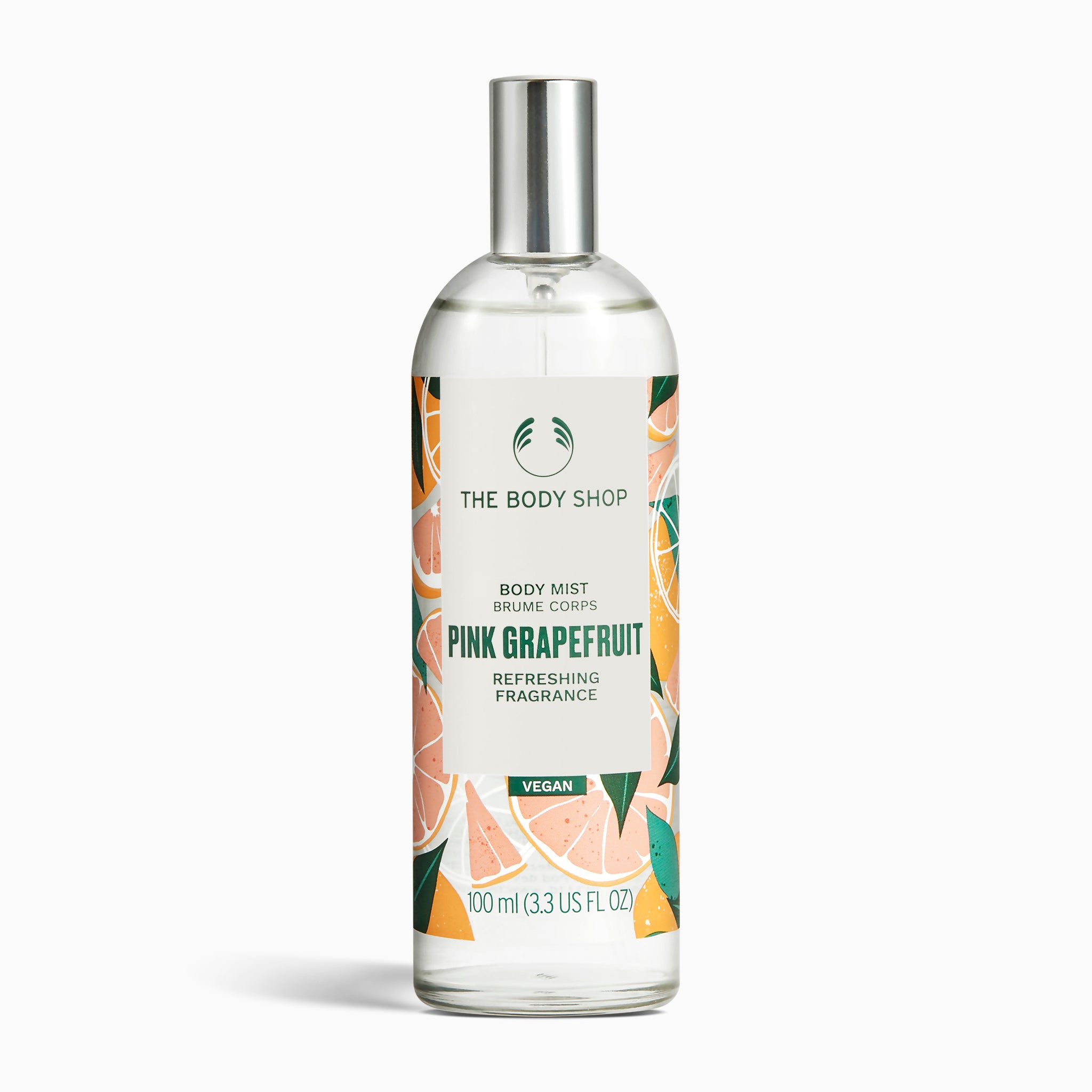 A bottle of The Body Shop Pink Grapefruit Body Mist 100 ML against a vibrant, fruity background.