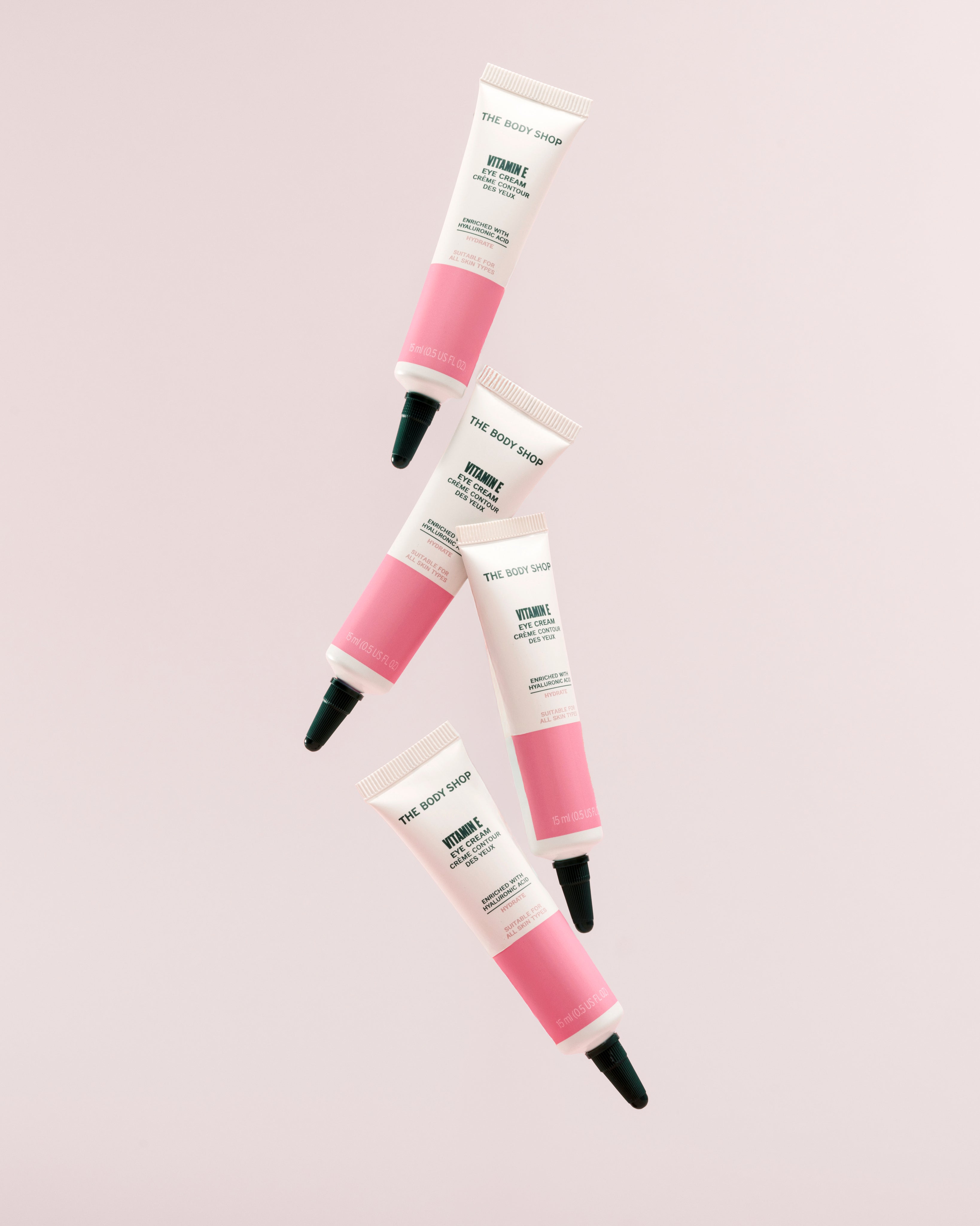 Arrangement of The Body Shop Vitamin E Eye Cream 15 ML against soft pink background