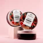 A colorful display of The Body Shop Strawberry Body Butter 200 ML against textured pink background.
