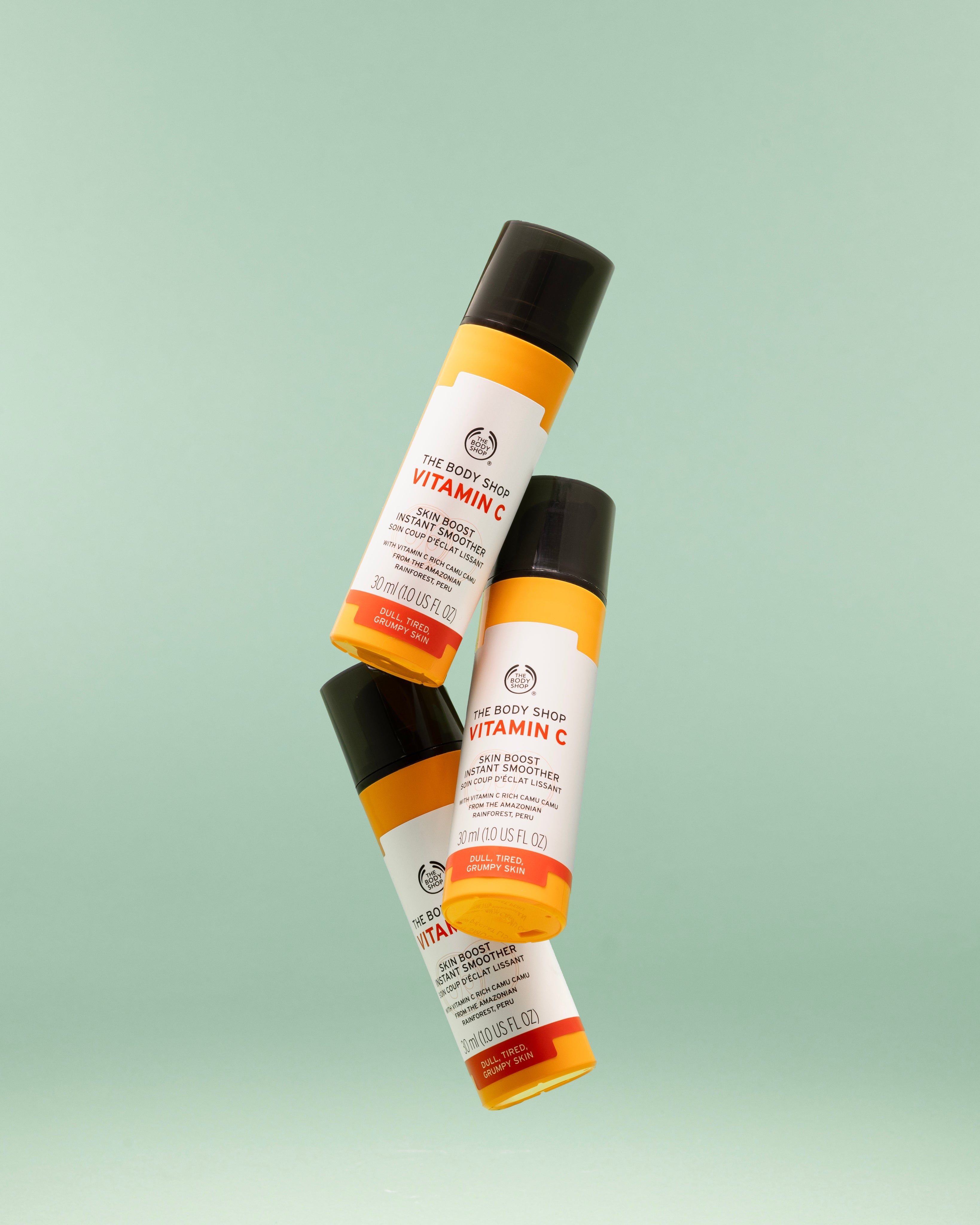 Three The Body Shop Vitamin C Skin Boost Instant Smoother 30 ML bottles displayed against a soft green background
