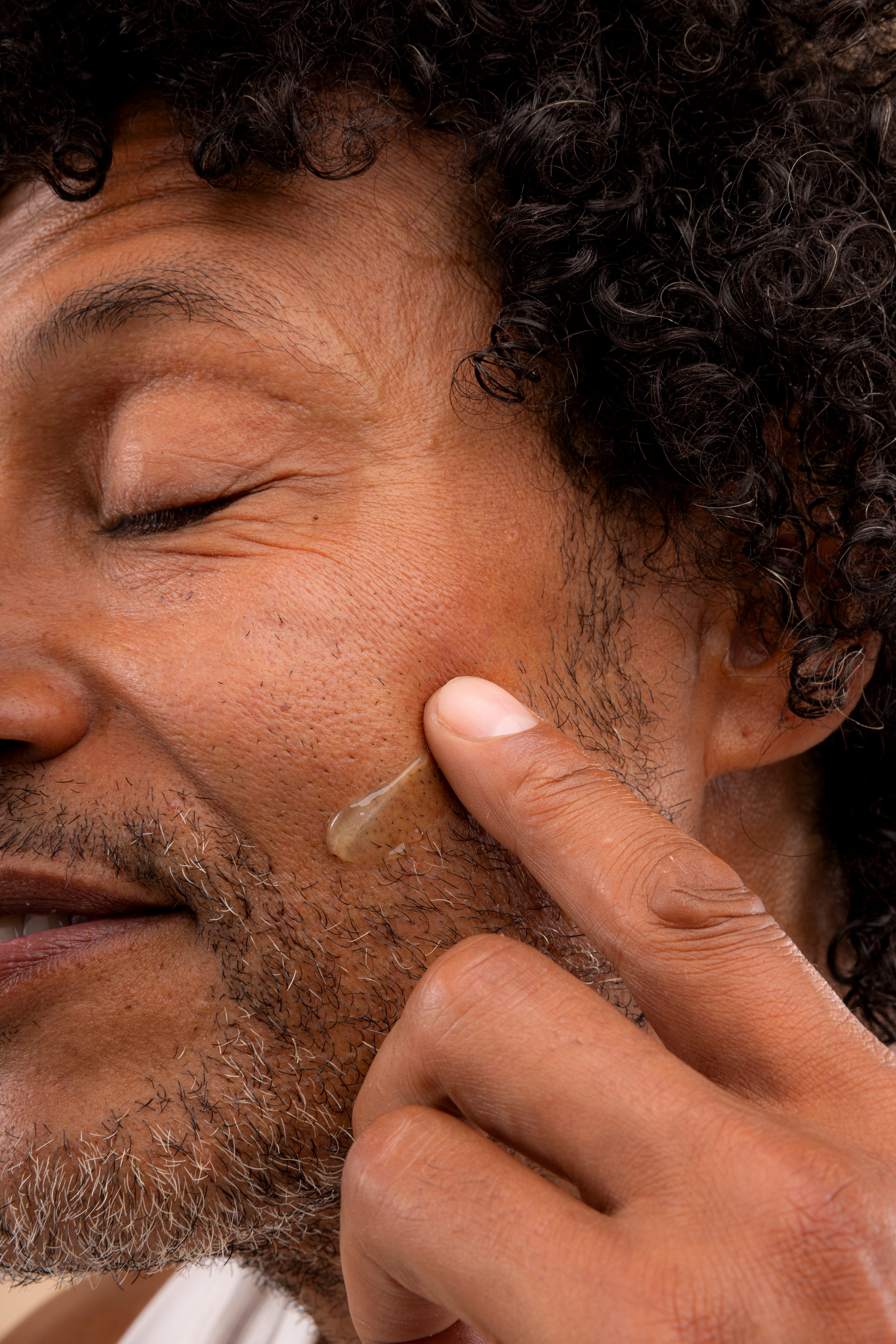Man applying The Body Shop Maca Root & Aloe Post Shave Water Gel 160 ML on his cheek after shaving.