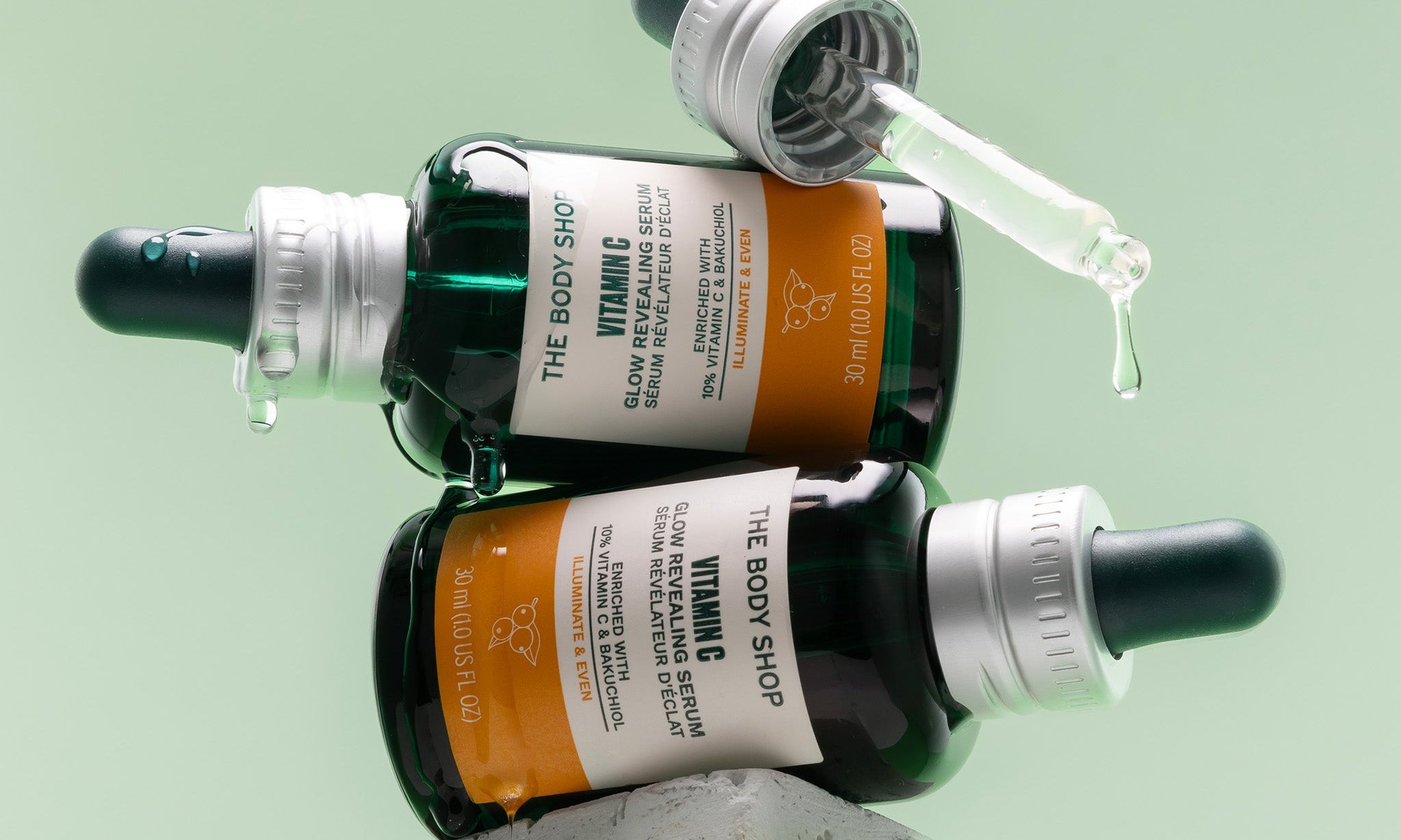 Two Vitamin C Glow Serum bottles on their side, stacked on top of one another, perched on a stone block.