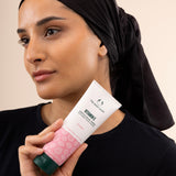 Woman holding The Body Shop Vitamin E Gentle Facial Wash 125ml against soft pastel background highlighting hydration.