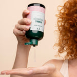 Person dispensing The Body Shop Vitamin E Moisturising Toner 250 ML in studio setting with backdrop
