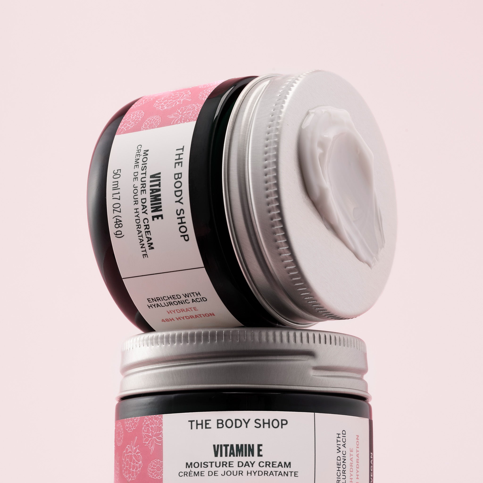 Two jars of The Body Shop Vitamin E Moisture Day Cream on a pink background