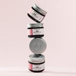 Stack of four jars of The Body Shop Vitamin E Intense Moisture Cream with a pink background