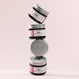 Stack of four jars of The Body Shop Vitamin E Intense Moisture Cream with a pink background
