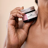 Woman holding The Body Shop Vitamin E Intense Moisture Cream 50 ML against skin in a studio setting