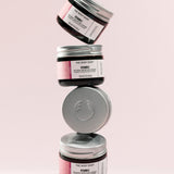 Stack of The Body Shop Vitamin E Intense Moisture Cream 50 ML jars against a soft pink background