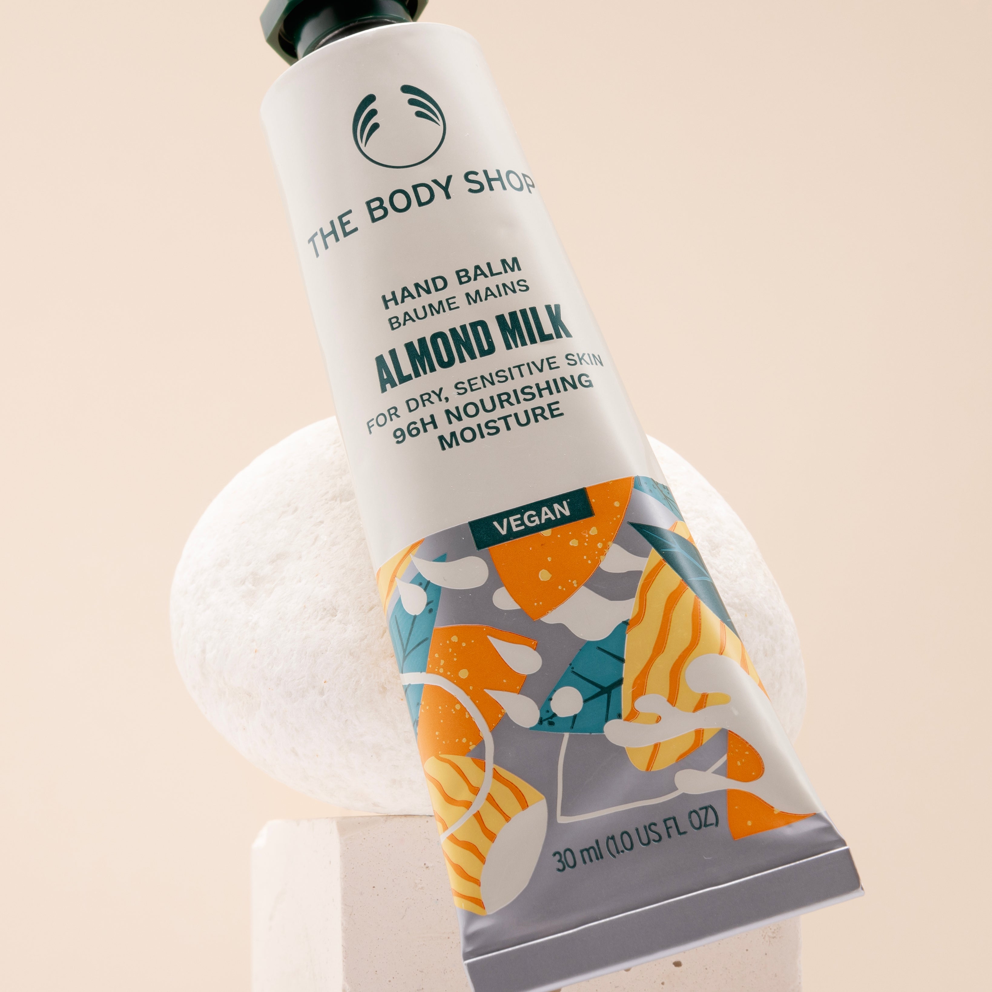 The Body Shop Almond Milk Hand Balm 30 ML on a stylish studio backdrop, showcasing nourishing properties.