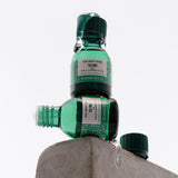 Two green bottles of The Body Shop Tea Tree oil on a white background