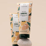 Two tubes of The Body Shop Almond Milk Body Lotion 200 ML elegantly displayed on a textured stone surface.