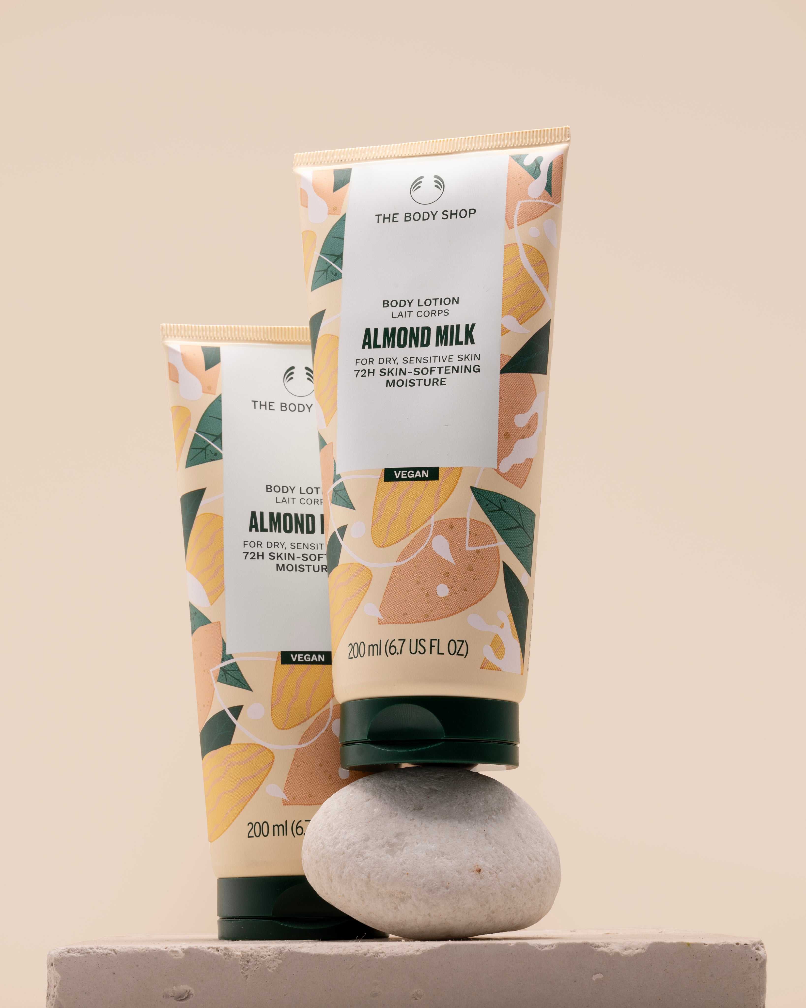 Two tubes of The Body Shop Almond Milk Body Lotion 200 ML elegantly displayed on a textured stone surface.