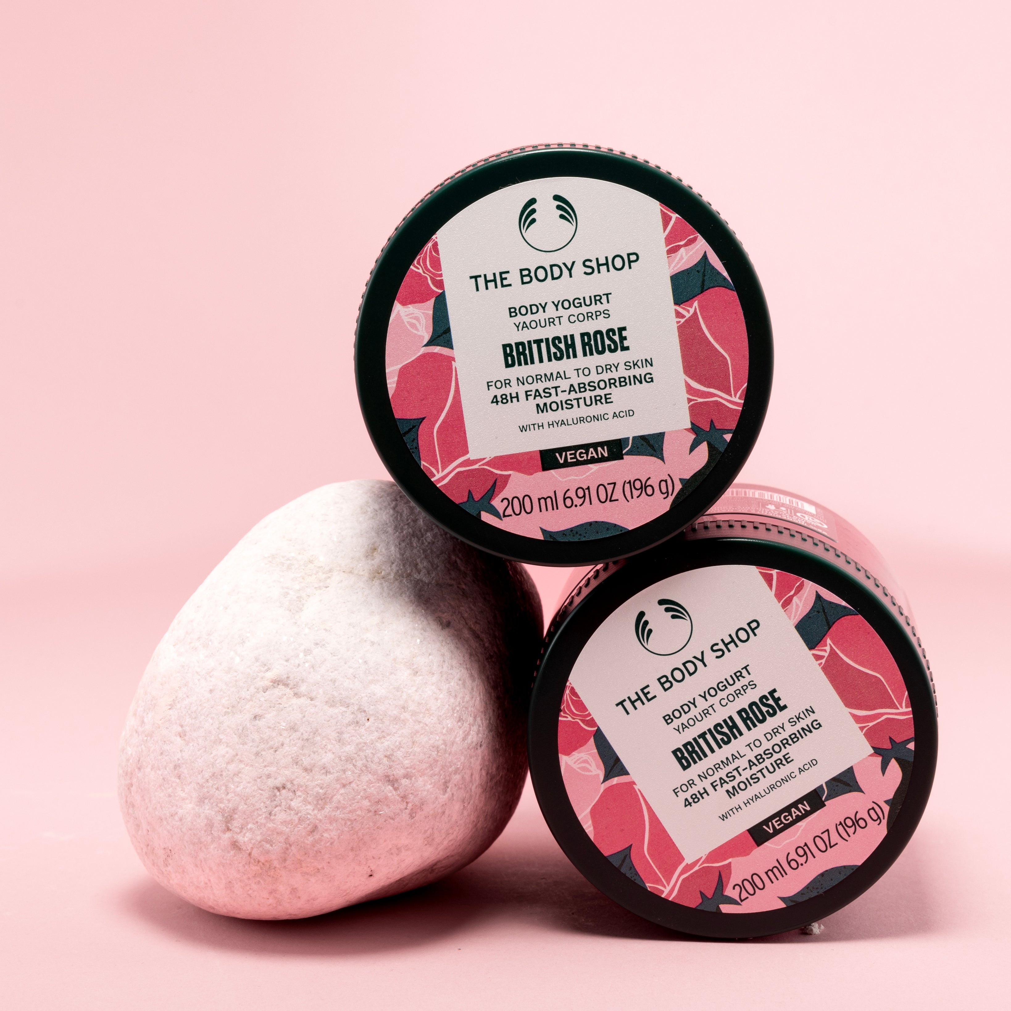 Two containers of The Body Shop British Rose Body Yogurt 200ml on a pink backdrop