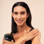Woman applying The Body Shop Strawberry Body Yogurt 650g on her arm against a soft, neutral background.