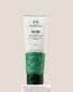 A tube of The Body Shop Tea Tree 3-in-1 Wash, Scrub, Mask 125ml displayed on a stone pedestal with a soft beige background.