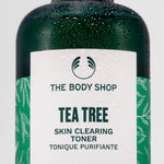 Close-up of The Body Shop Tea Tree Skin Clearing Toner, droplets on bottle against clean backdrop.