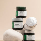 The Body Shop Edelweiss Bouncy Sleeping Mask 75ml displayed in an artistic arrangement of jars on neutral stones.