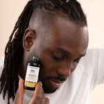 Man applying The Body Shop Ginger Scalp Serum 50 ML in studio setup with backdrop