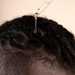 Hands applying Ginger Scalp Serum 50 ML in a professional studio setup with visible lighting gear.